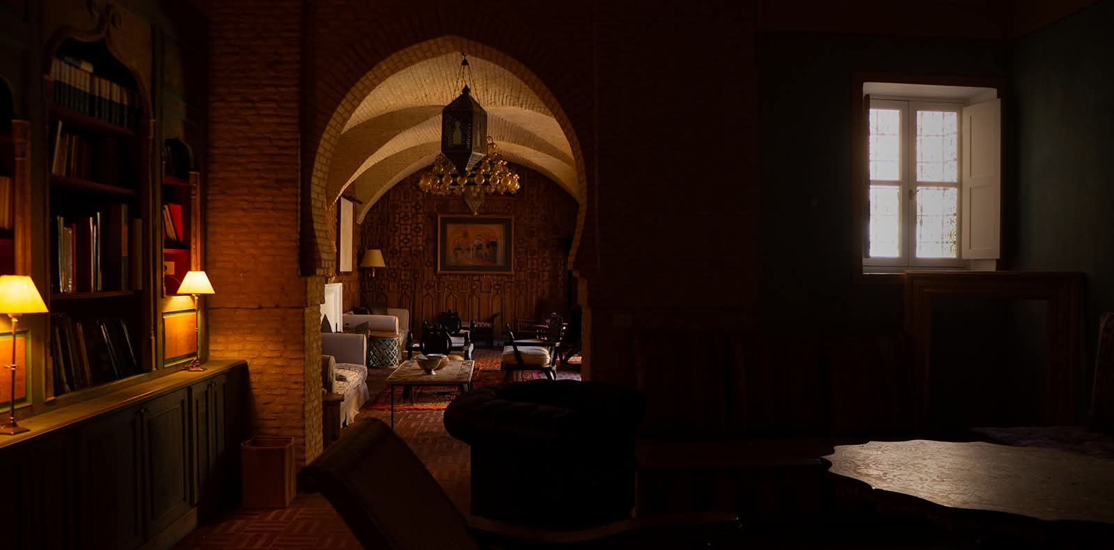 Enfilade sombre vers le salon voûté illuminé